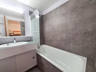 a bathroom with a sink and a tub and a mirror at Appartement Flaine Forêt in Flaine