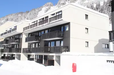 a building in the snow with a mountain in the background at Résidence Gemeaux - Studio confortable · Centre station · Balcon MAE-7844 in Magland