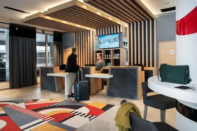 a lobby with two people standing at a counter at MGM Hôtels & Résidences - Résidence Alhéna in Flaine