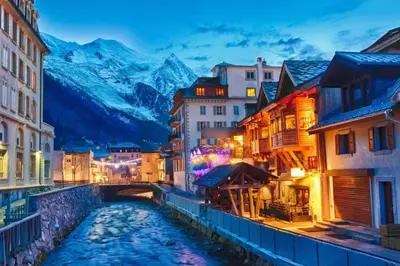 a river in a city with mountains in the background at Apartment Relais de Poste Centre Chamonix Mont Blanc in Chamonix-Mont-Blanc