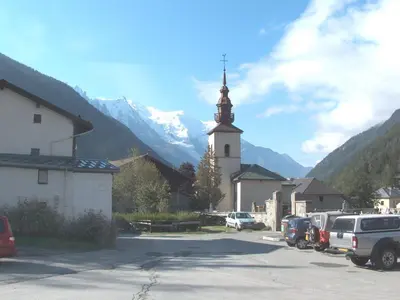 a church with a steeple and cars parked in a parking lot at Apartment Village des Oursons Chalet A4 by Interhome in Chamonix-Mont-Blanc