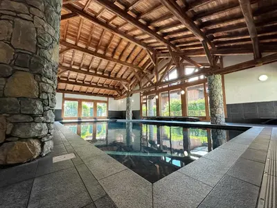 a swimming pool in a building with a stone wall at Spacieux duplex dans une résidence avec piscine - FR-1-624-137 in Samoëns