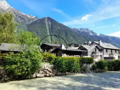 a house next to a river with mountains in the background at Chalet Marguerite by Brennus Chamonix in Chamonix-Mont-Blanc