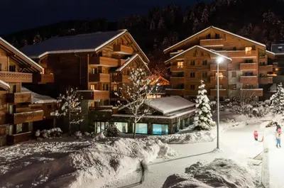 a lodge in the snow with people walking in front of it at Résidence Les Fermes du Soleil - maeva Home - Appartement 3 pièces 5 personnes - Sélection MAE-9504 in Les Carroz d'Araches