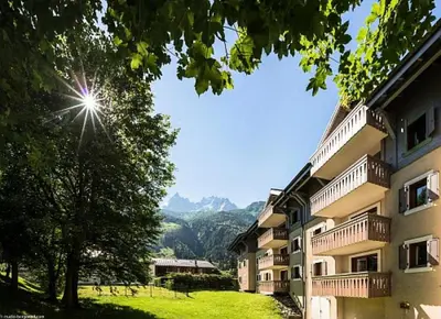 a view of a building with mountains in the background at Résidence La Ginabelle - maeva Home - Appartement 3 pièces 6 personnes - Prestige MAE-4044 in Chamonix-Mont-Blanc