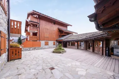 an empty courtyard of a building with wooden buildings at Résidence Les Fermes du Soleil - maeva Home - Appartement 3 pièces 6 personnes Sélection MAE-1439 in Les Carroz d'Araches