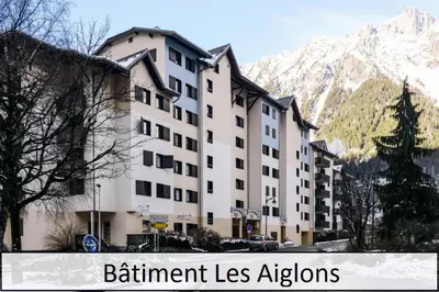 a building in front of a mountain with the words retirement lessensions at L'Aiguille - maeva Home - 2 Pièces 5 Personnes Confort MAE-1176 in Chamonix-Mont-Blanc