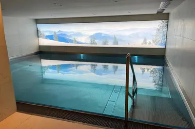 a swimming pool with a large window in a building at Appartement du Cerf - Welkeys in Megève
