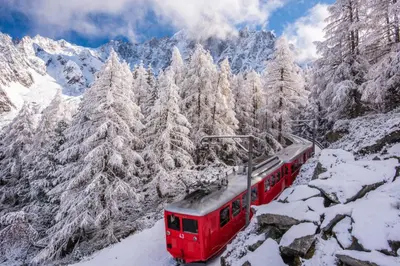 a red train traveling through the snow covered mountains at Amethyste - 2 Bedrooms & Free Parking - By Cozee Rentals in Les Houches