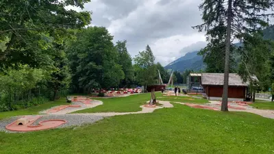 a park with benches and a building and trees at Studio au pied des remontées/wifi/smart TV/parking in Les Contamines-Montjoie