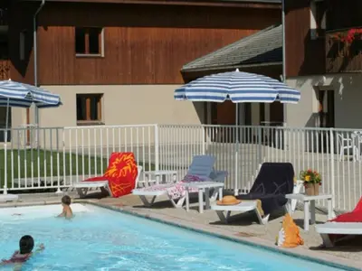 a pool with chairs and umbrellas and people in the water at 3 pièces avec terrasse, animaux admis, parking – Samoëns - FR-1-629-137 in Samoëns
