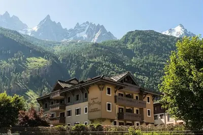 a large apartment building with mountains in the background at Résidence La Ginabelle - maeva Home - Appartement 4 Pièces 8 Personnes - Sélection MAE-1965 in Chamonix-Mont-Blanc