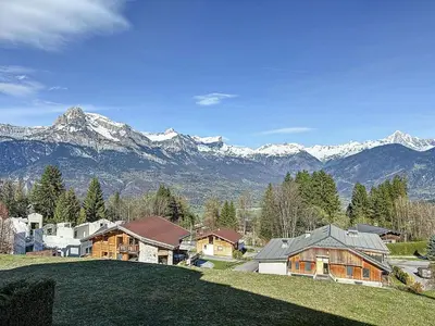 a house on a hill with mountains in the background at Charmant 3 pièces avec jardin, parking et proximité ski bus à 900m du village de Combloux - FR-1-560-121 in Combloux