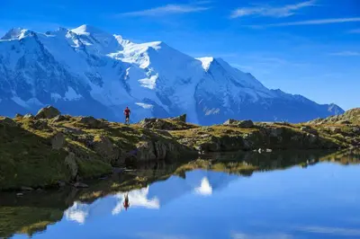 a man standing on the edge of a lake in front of a mountain at Studio de Balme - Happy Rentals in Chamonix-Mont-Blanc