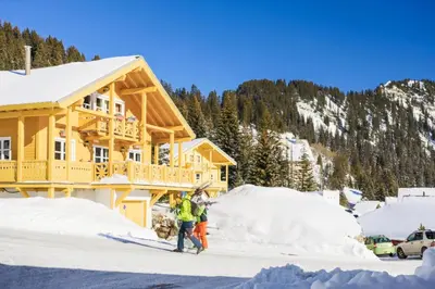 two people standing in the snow in front of a house at Les Chalets de Flaine Hameau - maeva Home - Chalet 5 Pièces 8 Personnes - Sélection MAE-2135 in Flaine