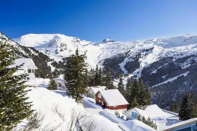 a snow covered mountain with a house in the foreground at Les Chalets de Flaine Hameau - maeva Home - Chalet 5 Pièces 10 Personnes - Exclusive MAE-0944 in Flaine