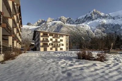 a building in the snow with mountains in the background at Lac des Gaillands - Renove - Balcon avec vues in Chamonix-Mont-Blanc