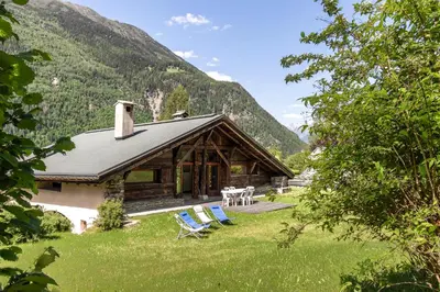 a log cabin with chairs and a table in the grass at La Poya haut - Calme - Vues magnifiques in Les Houches
