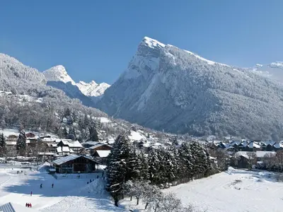 a village in the snow with a mountain in the background at Bel appartement T3 en résidence neuve avec parking et WIFI, proche du village et ski-bus - FR-1-624-168 in Samoëns