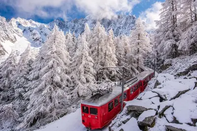 a red train traveling through the snow covered mountains at Lognan- New studio in the city center - By Cozee Rentals in Chamonix-Mont-Blanc