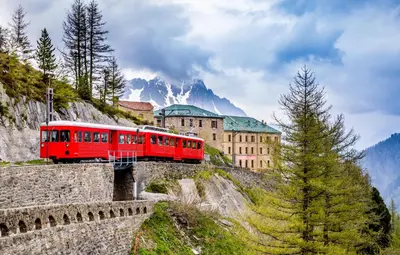 a red train on a bridge over a mountain at Clos Savoy - New Apartment Close to City center & Free parking - By Cozee Rentals in Chamonix-Mont-Blanc