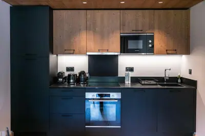 a kitchen with black cabinets and a stove and a microwave at Exclusive accommodation terrace, parking and pool in Megève