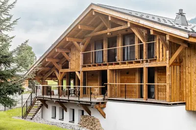 a large timber house with a large deck at Chalet de 8 chambres MEGEVE - 16 personnes in Megève