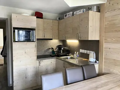a kitchen with wooden cabinets and a counter top at Résidence Le Panoramic - Appartement lumineux · Départ et retour skis aux pieds · Piscine · Parking inclus · Spa · wifi MAE-0351 in Magland