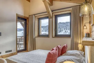 a bedroom with a bed and windows with a view at Chalet Alpestre in Combloux