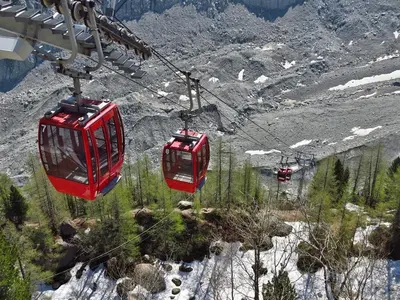 two red cable cars flying over a mountain at Apartment Maisonnee - A Charming Chamonix Haven in Chamonix-Mont-Blanc