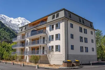 a large white building with a mountain in the background at Paradisa Mer de Glace Elegant brand new 3-bedroom apartment in Chamonix-Mont-Blanc