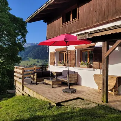 a wooden deck with a red umbrella on a house at Gîte de l Auguille in Megève