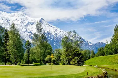 a golf course with a snow covered mountain in the background at Diamond - Hyper Central 2 Bedrooms - Magnificent Views - By Cozee Rentals in Chamonix-Mont-Blanc