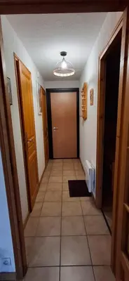 a hallway with a door and a tiled floor at Bel appartement in Samoëns