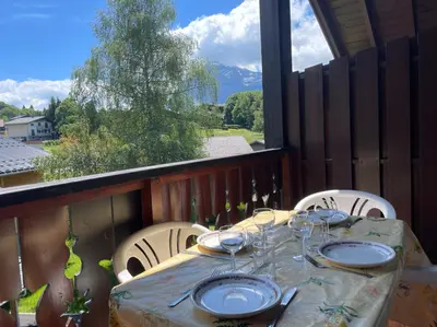 a table with plates and wine glasses on a balcony at Duplex with fantastic view 3 bedrooms 7-9 pers in Arâches-la-Frasse
