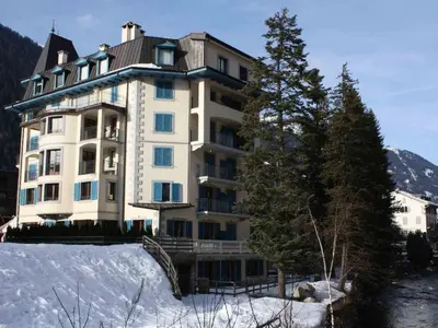 a large building in the snow next to a tree at Apartment Charmante Wohnung in Chamonix mit Südbalkon und Blick auf den Blanc by Interhome in Chamonix-Mont-Blanc