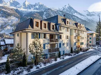 a large apartment building with mountains in the background at Apartment Wohnung in Chamonix Centre-Ville by Interhome in Chamonix-Mont-Blanc