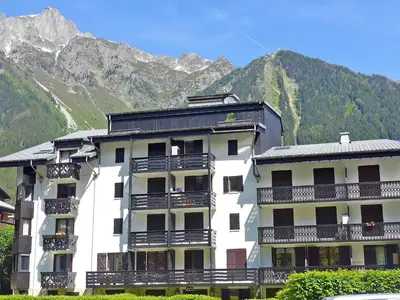 a white building with balconies and mountains in the background at Studio Le Triolet-6 by Interhome in Chamonix-Mont-Blanc