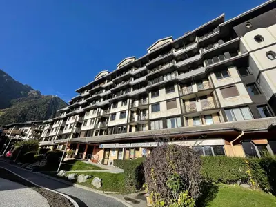 a large apartment building with mountains in the background at Apartment Le Chamois Blanc-10 by Interhome in Chamonix-Mont-Blanc