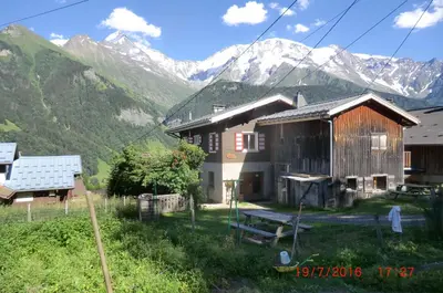 a couple of buildings with mountains in the background at Les passereaux in Saint-Nicolas-de-Véroce