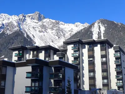 a building with mountains in the background at Studio L'Aiguille du Midi-7 by Interhome in Chamonix-Mont-Blanc