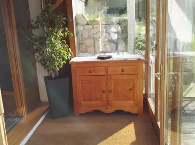 a wooden cabinet in front of a glass door at Appartement cosy aux Carroz, 40 m², vue sur la montagne in Les Carroz d'Araches