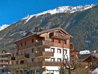 a large building with mountains in the background at Apartment L'Espace Montagne-11 by Interhome in Chamonix-Mont-Blanc