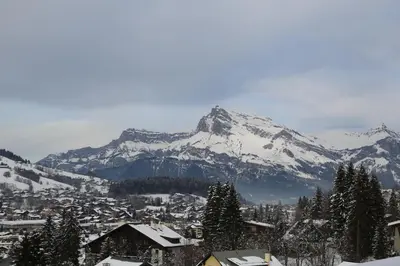 a snow covered mountain in front of a town with houses at Fabulous Residence Lesporting Ski - AE203 in Megève