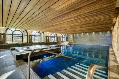 an indoor swimming pool with a wooden ceiling at The Drus Luxury Apartment with Spa and Indoor Pool in Chamonix-Mont-Blanc