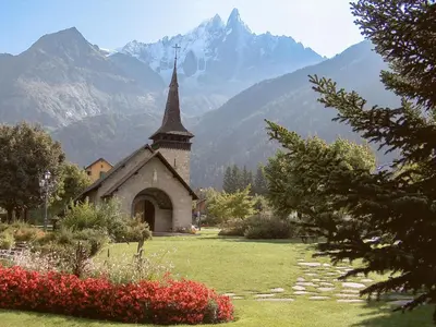a church in a field with mountains in the background at Apartment Champraz-15 by Interhome in Chamonix-Mont-Blanc