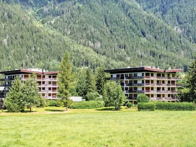 two buildings in a field next to a mountain at Apartment Le Bois du Bouchet-1 by Interhome in Chamonix-Mont-Blanc