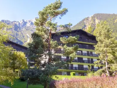 a hotel with trees and mountains in the background at Apartment Le Brévent-14 by Interhome in Chamonix-Mont-Blanc
