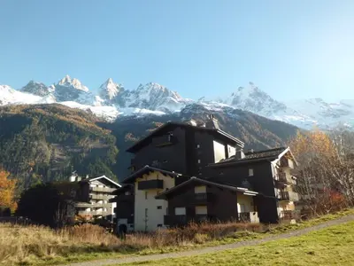 a house on a hill with mountains in the background at Studio cosy proche des pistes - Animaux admis - FR-1-517-52 in Chamonix-Mont-Blanc