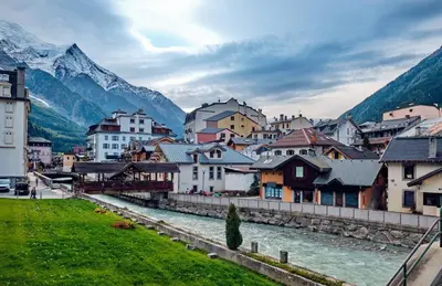 a town with a river and mountains in the background at Apartment Genevrier - Spacious Balcony with Mont Blanc Views in Chamonix-Mont-Blanc